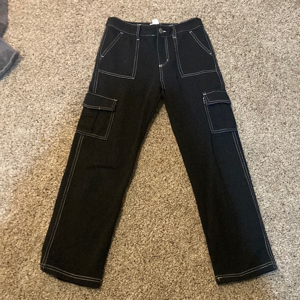 Black cotton cargo pants with white stitching.